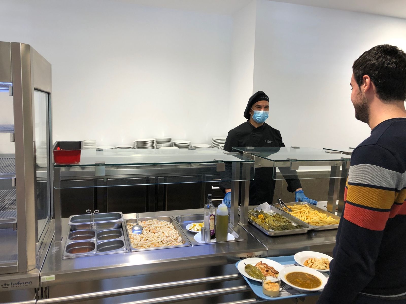 Uno de los estudiantes confinados recoge el almuerzo en el comedor del colegio mayor de la UCA.