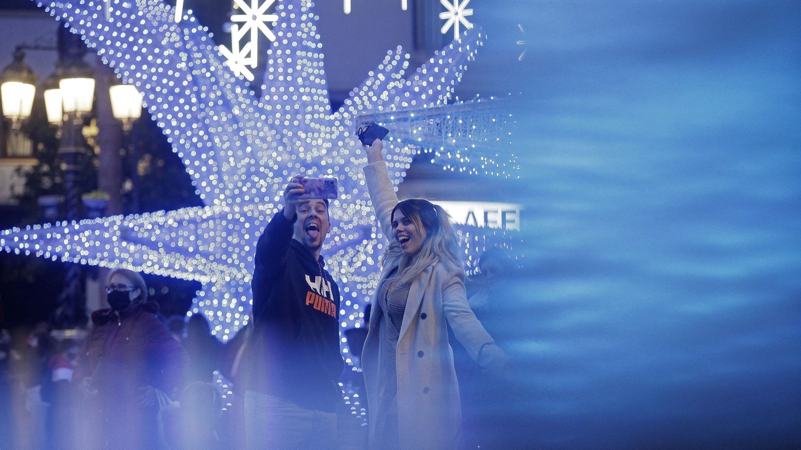 Una pareja se hace un selfie con el alumbrado navideño de la plaza Alta de Algeciras