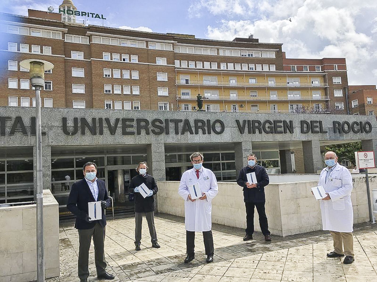 El delegado del Gobierno de la Junta en Sevilla, Ricardo Sánchez, y el director de Relaciones Institucionales de El Corte Inglés, Fernando Murube, hacen entrega de las tablets a Manuel Molina, gerente del Hospital Virgen del Rocío.