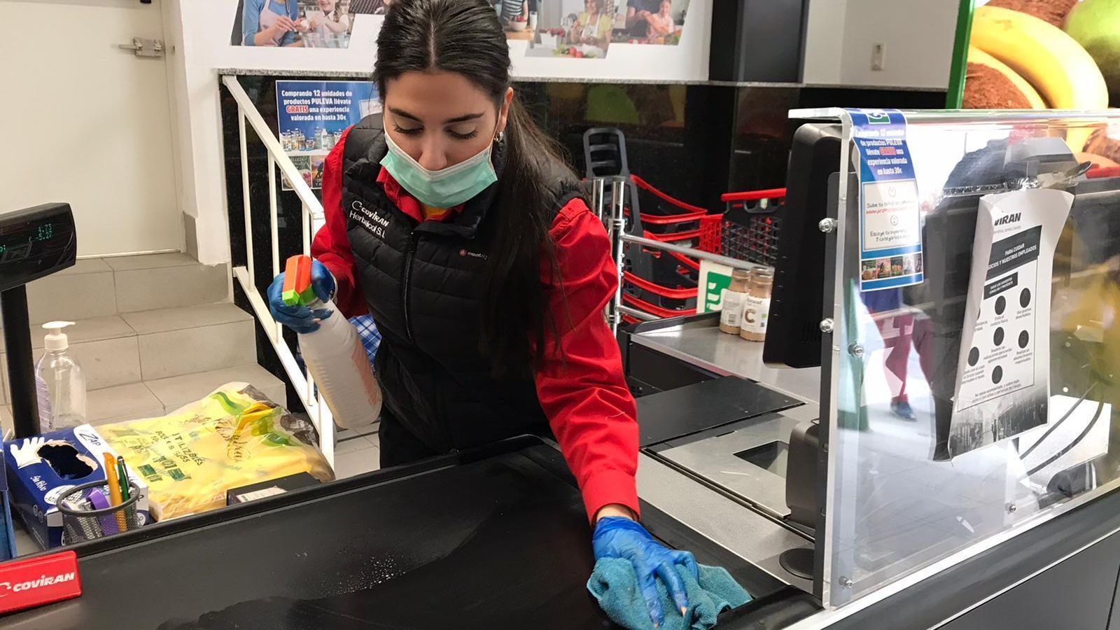 Una de las cajeras desinfecta la cinta antes del siguiente cliente.