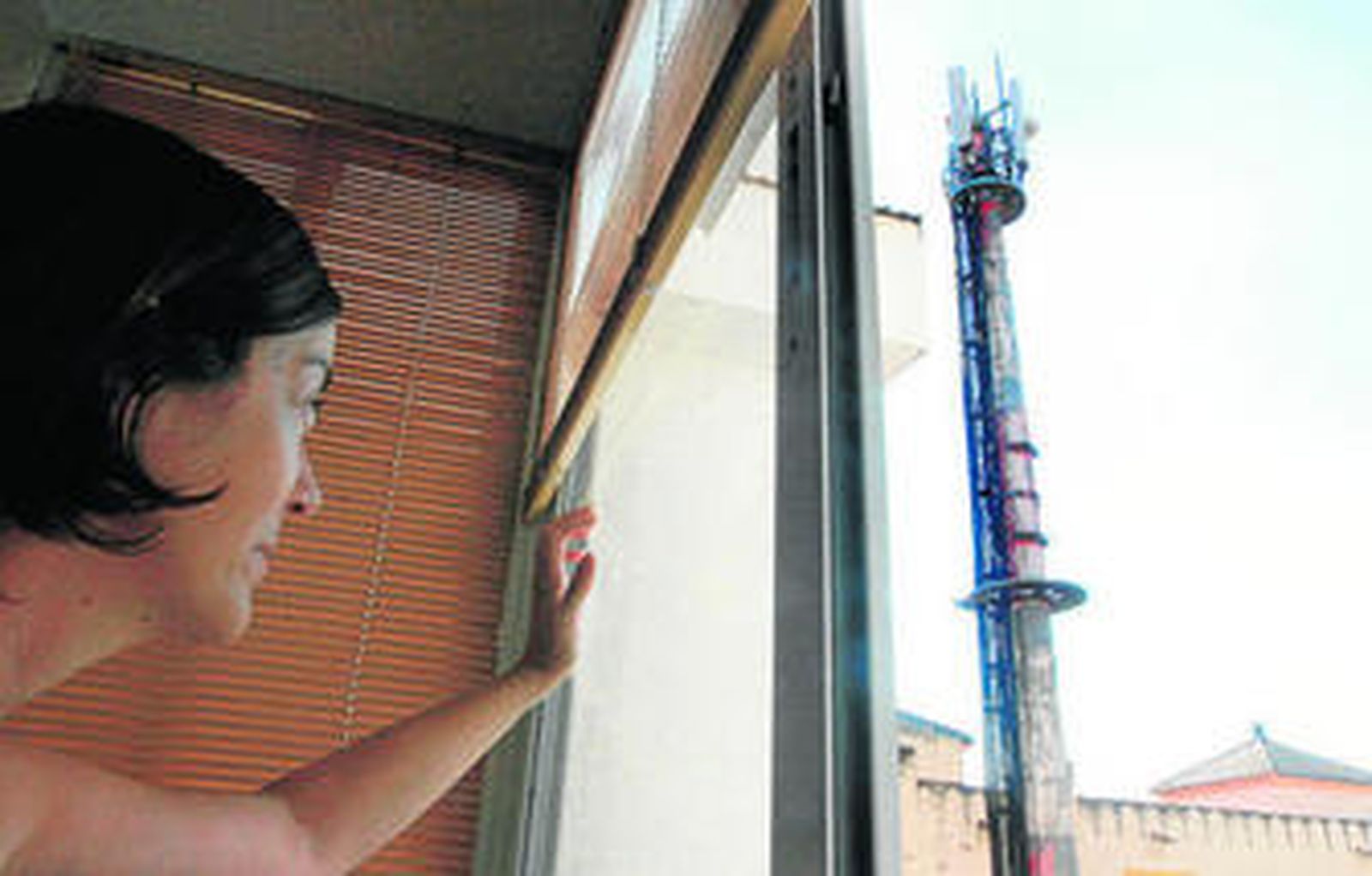 Una vecina afectada observa la antena telefónica que causa los ruidos.