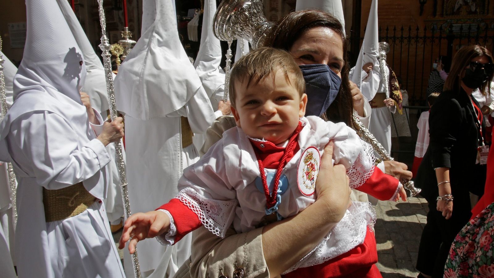 Carmen Gavira lleva a su hijo Antonio en brazos en su primera salida como monaguillo de la Cena