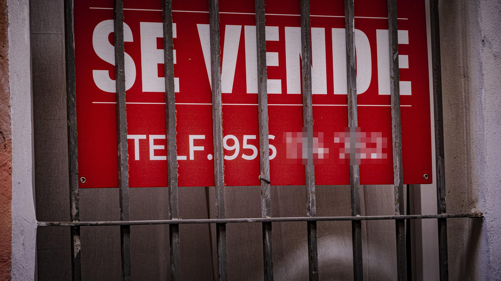 Un cartel de Se Vende tras la reja de una vivienda