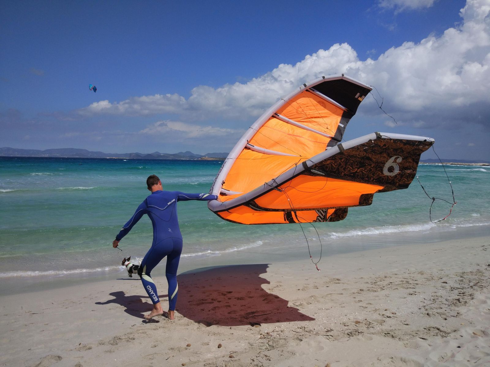 Un surfero aprovecha el viento idóneo para adentrarse en las aguas de Les Illetes y practicar 'kitesurf'.