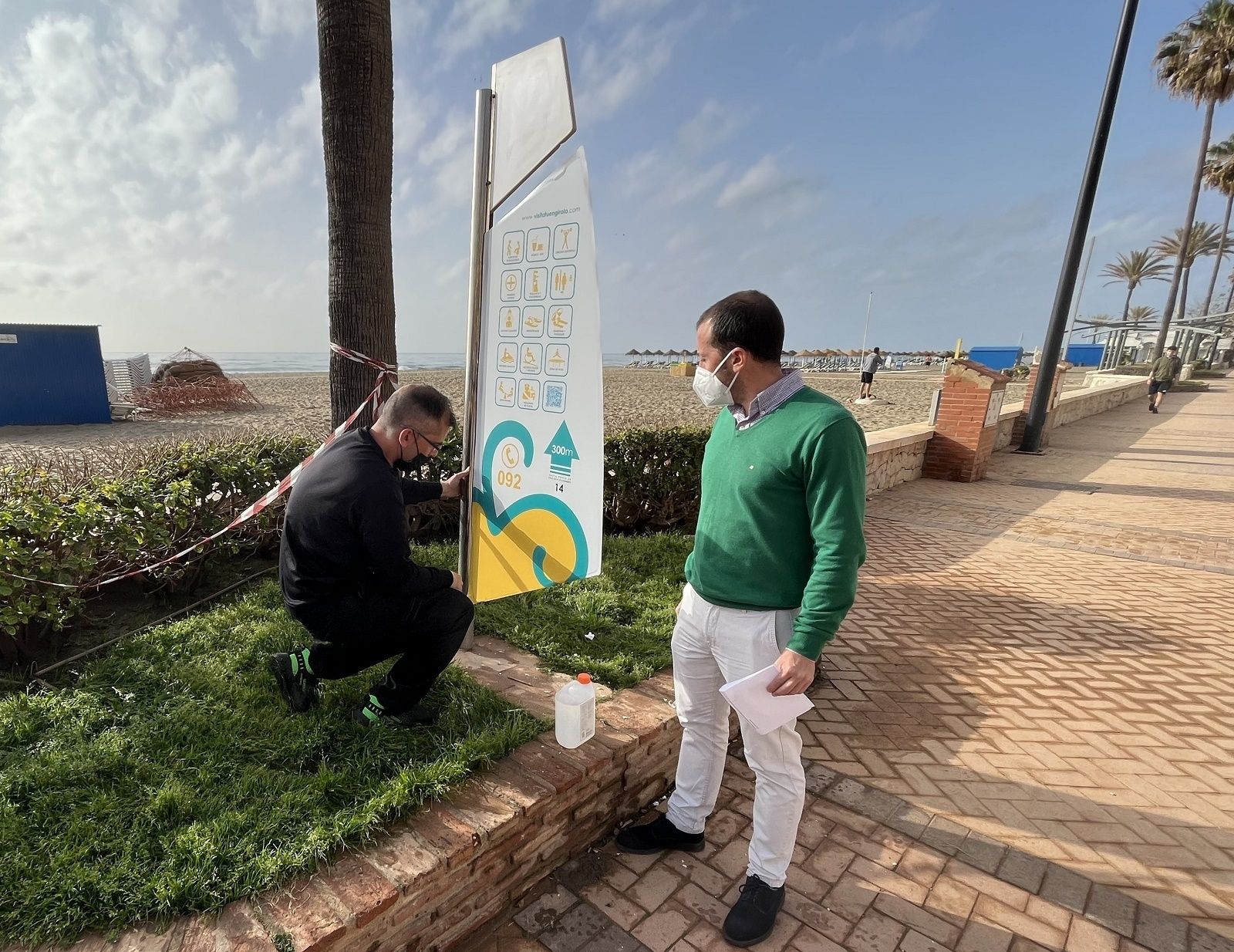 Un operario cambia la cartelería en el paseo marítimo.