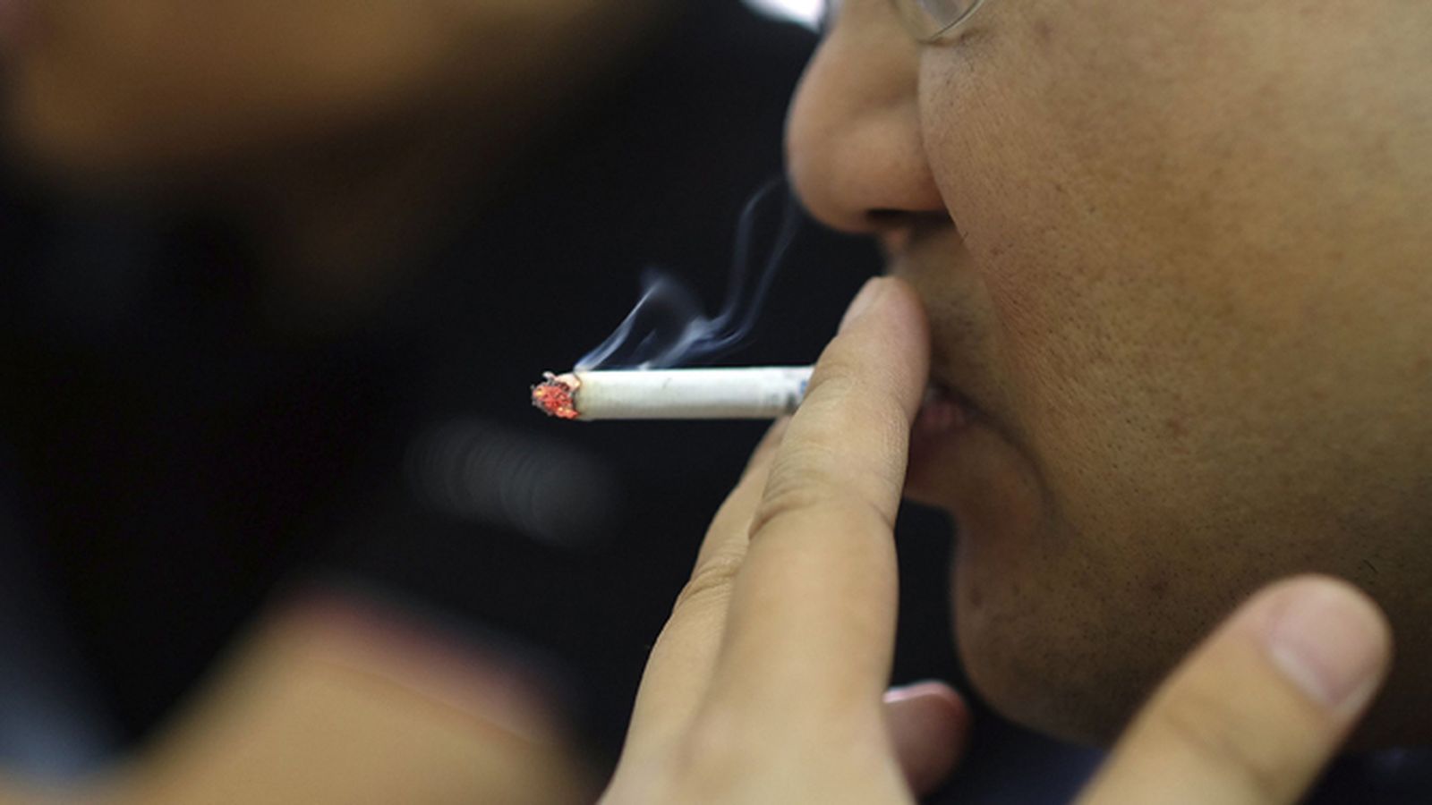 Un hombre fuma un cigarrillo.