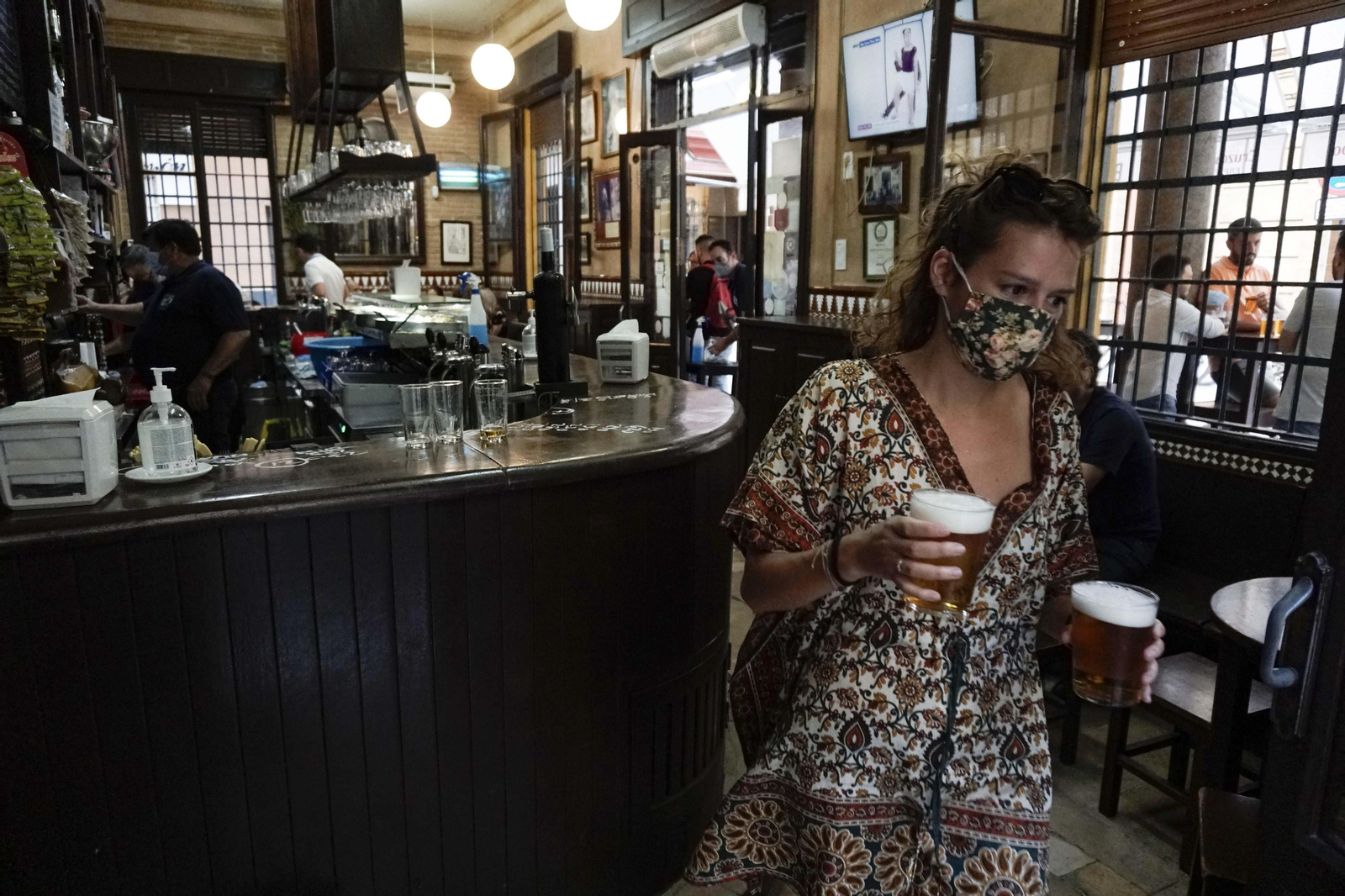 Una mujer saca dos cervezas del interior de un bar