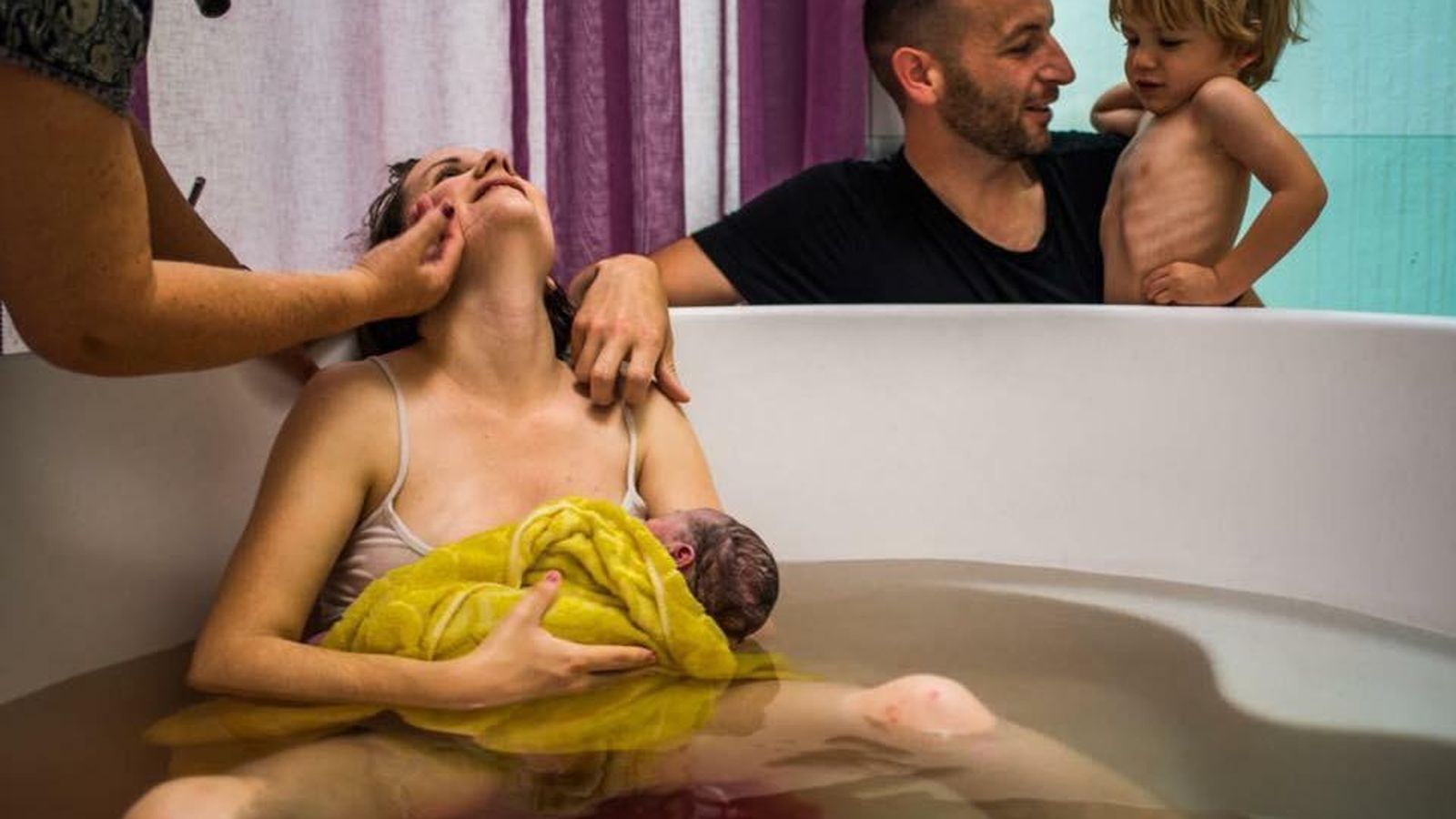 Irene Anguas, tras a dar a luz a su segundo hijo, atendida por su matrona, Maite, junto a su marido y a su primer hijo.