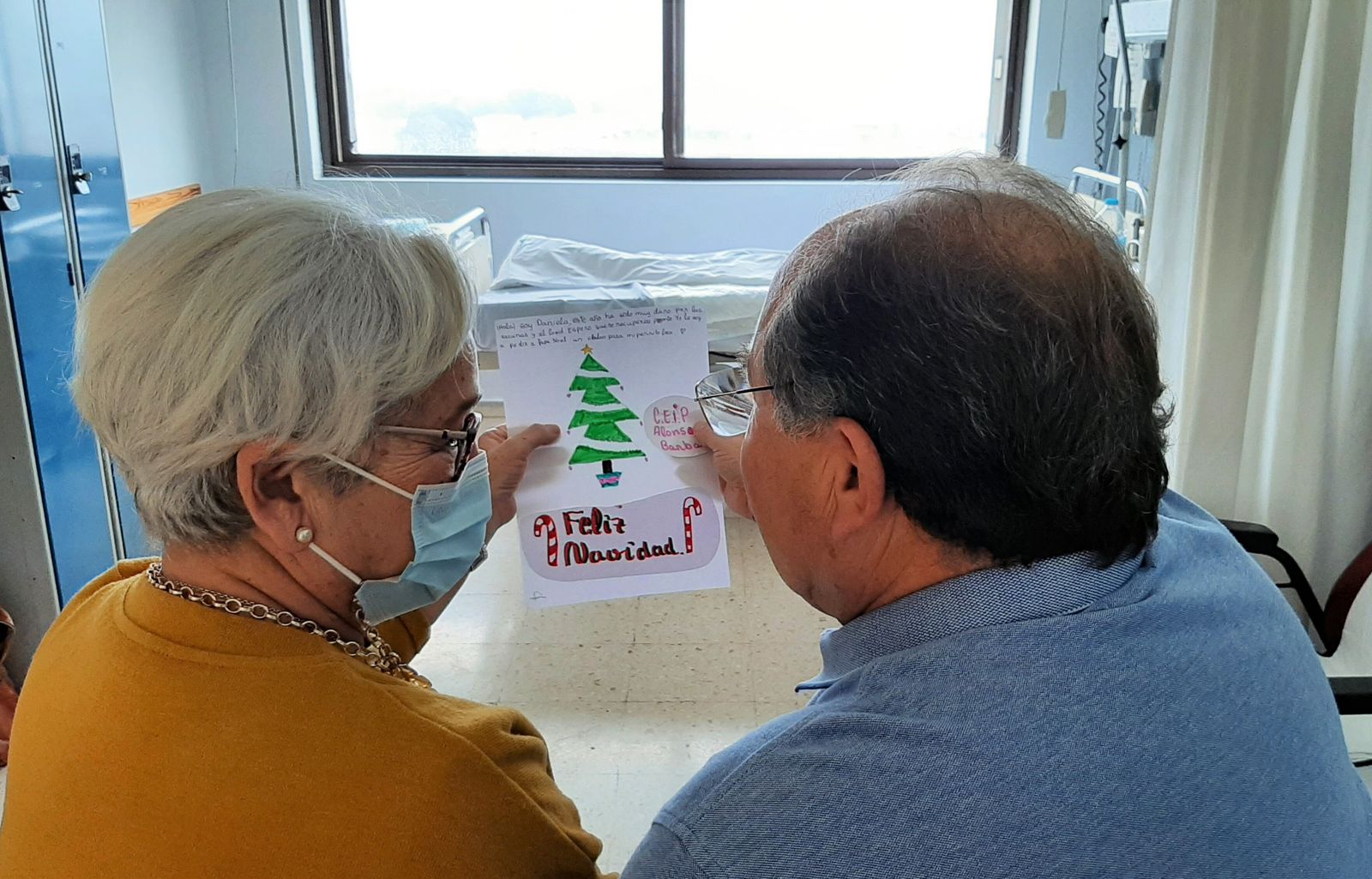 Dos personas leen una de las felicitaciones elaboradas por los niños.