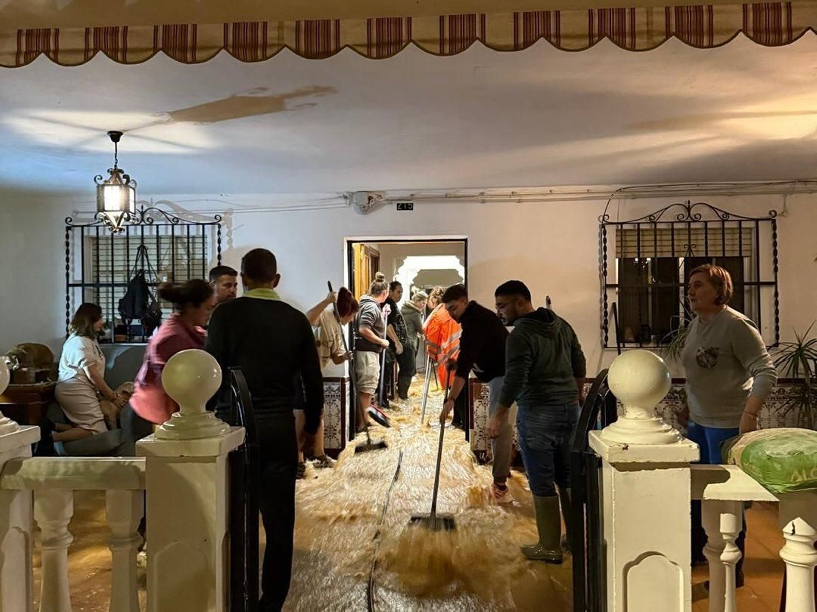 Vecinos achican agua de una vivienda anegada en la barriada de Los Mochos de Almodóvar del Río.