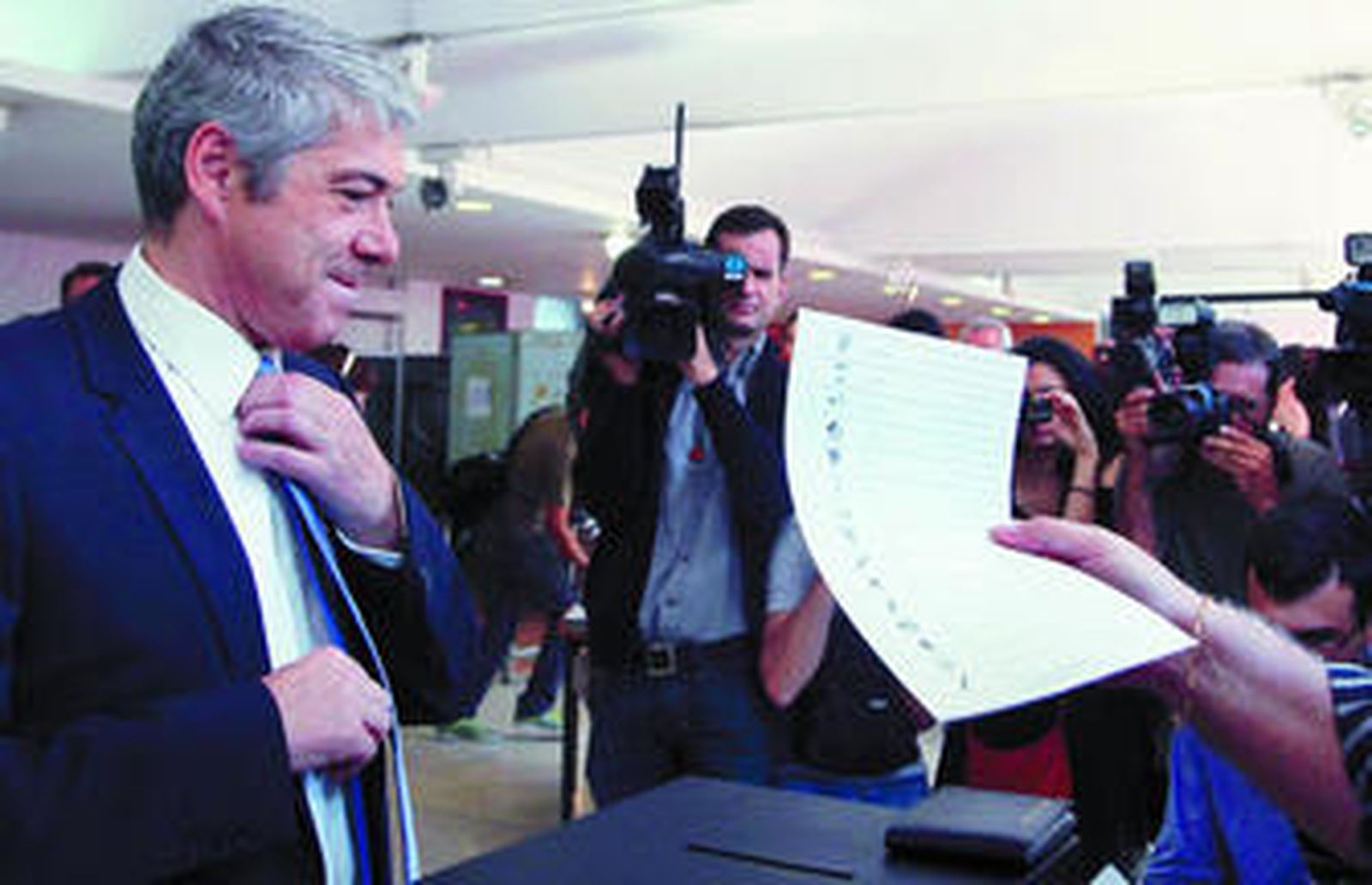 Sócrates se ajusta el nudo de la corbata en el momento de depositar su voto.