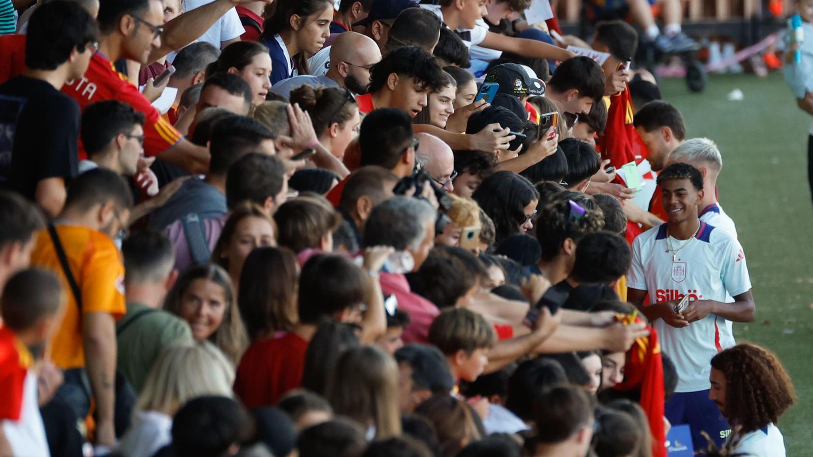El delantero Lamine Yamal firma autógrafos al público asistente durante el entrenamiento de la selección española.