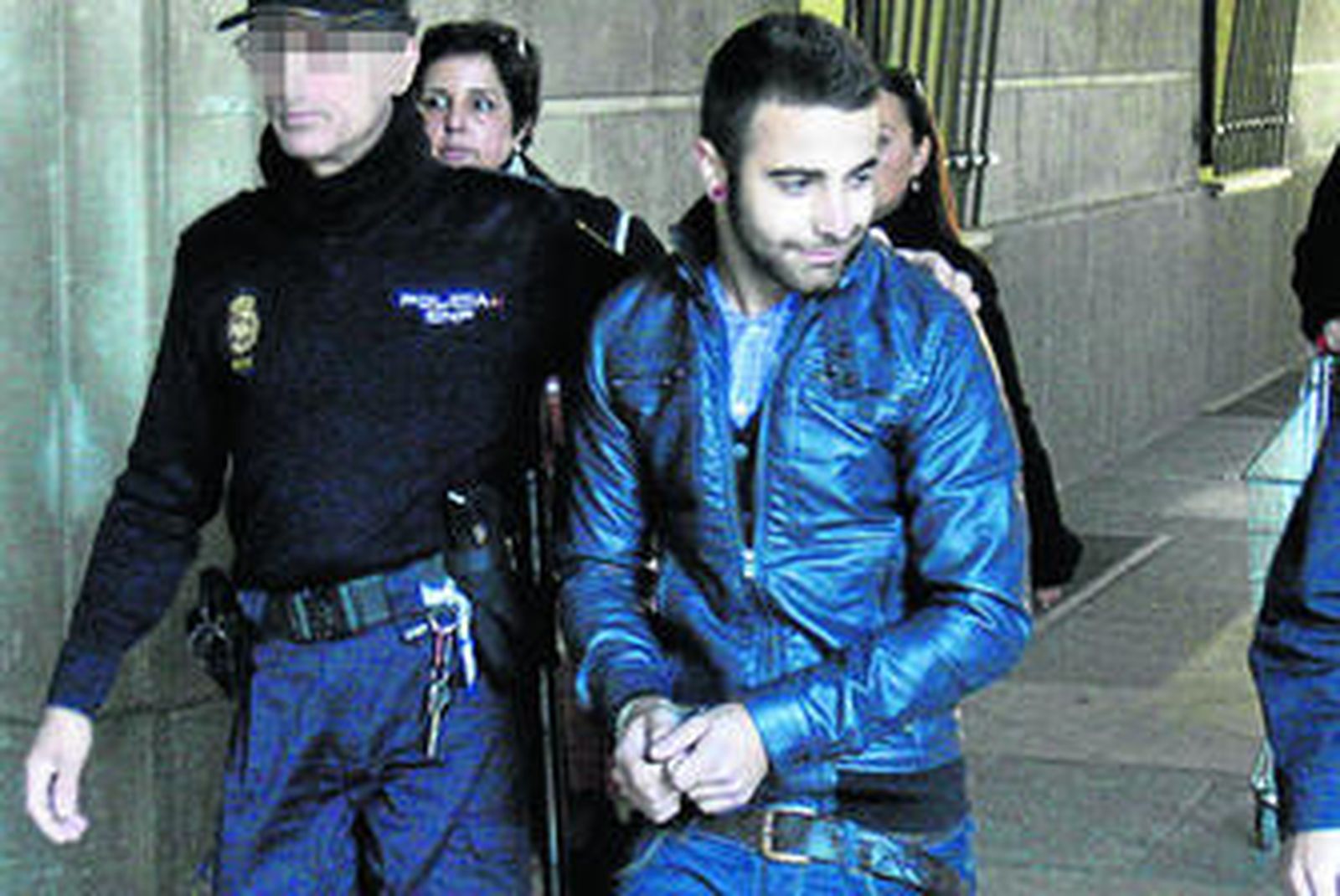 Uno de los jóvenes imputados es conducido ante el juez por los policías tras ser detenido.