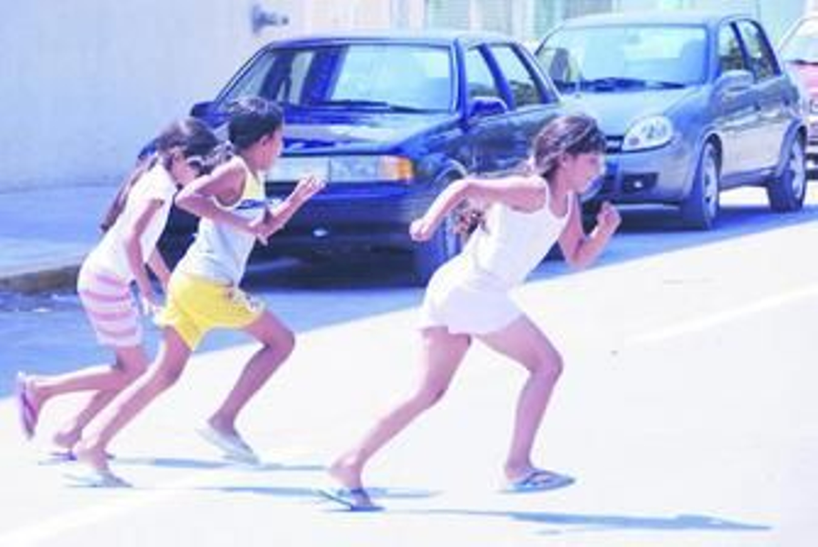 Unas niñas cruzan la carretera corriendo por un lugar no permitido.