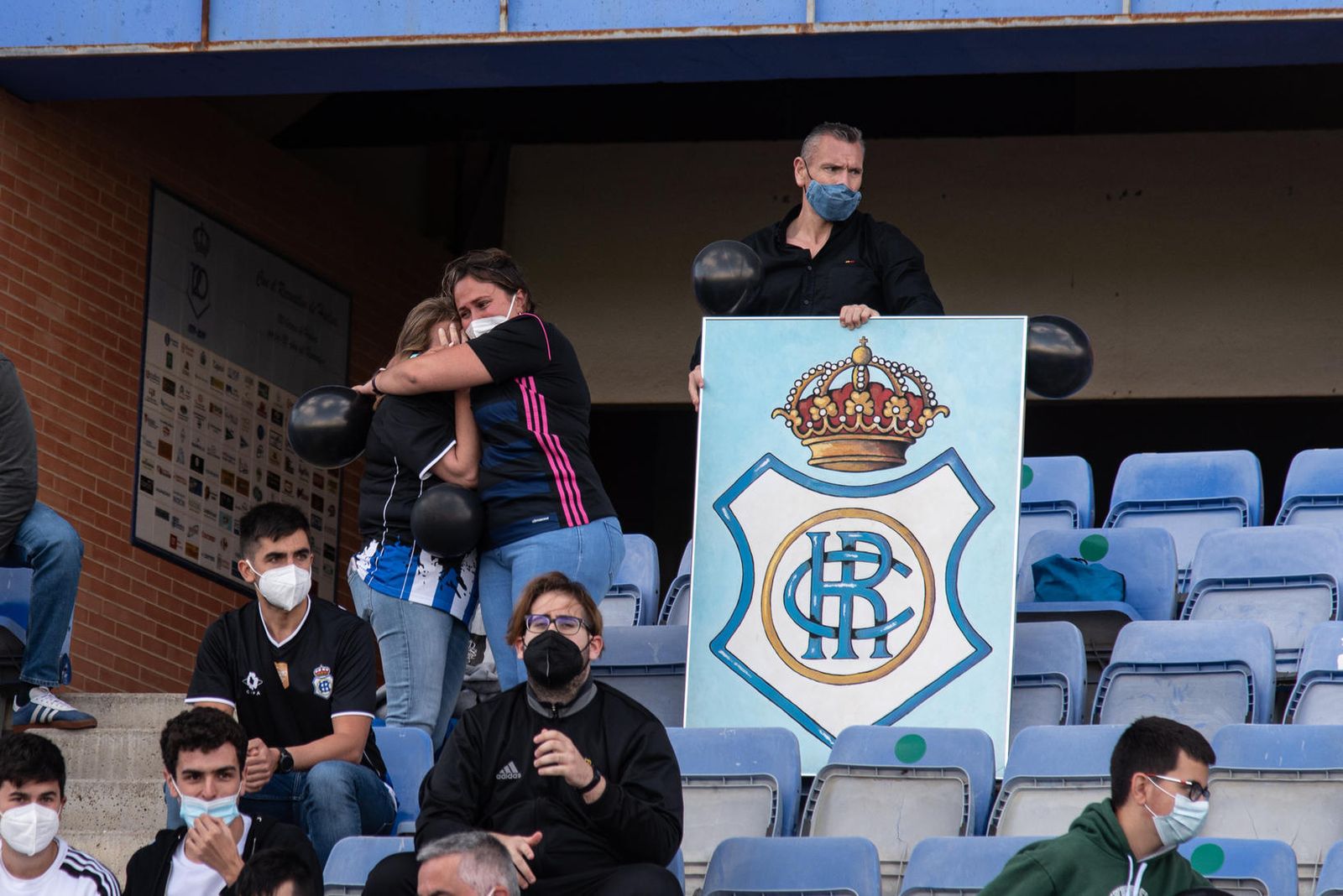 Aficionados del Recreativo de Huelva, desolados por el descenso de su equipo, portan globos negros.
