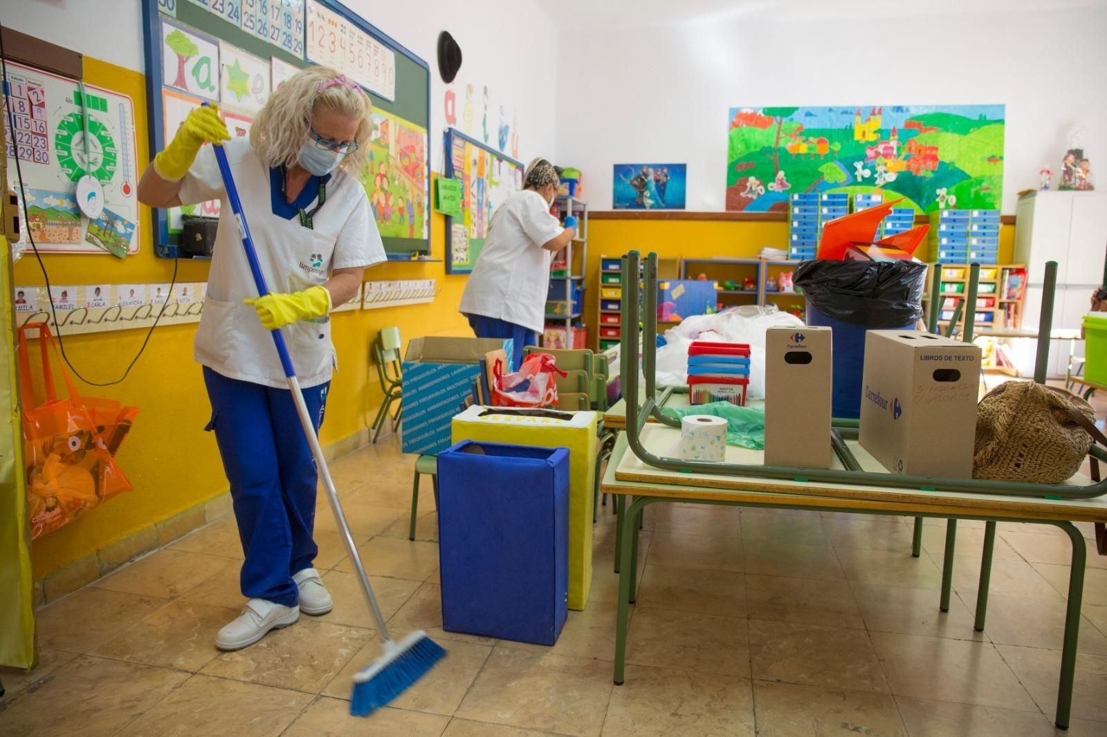 Dos limpiadoras trabajan en una aula.