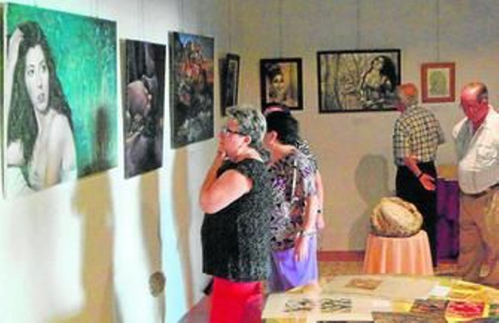 Un grupo de visitantes observa algunas de las pinturas y esculturas de la muestra.