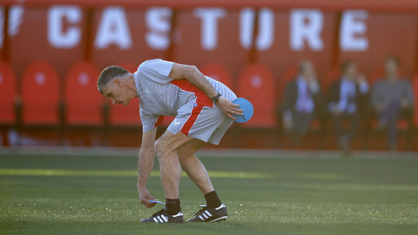 El veterano técnico de 62 años se agacha para colocar señales de posición.