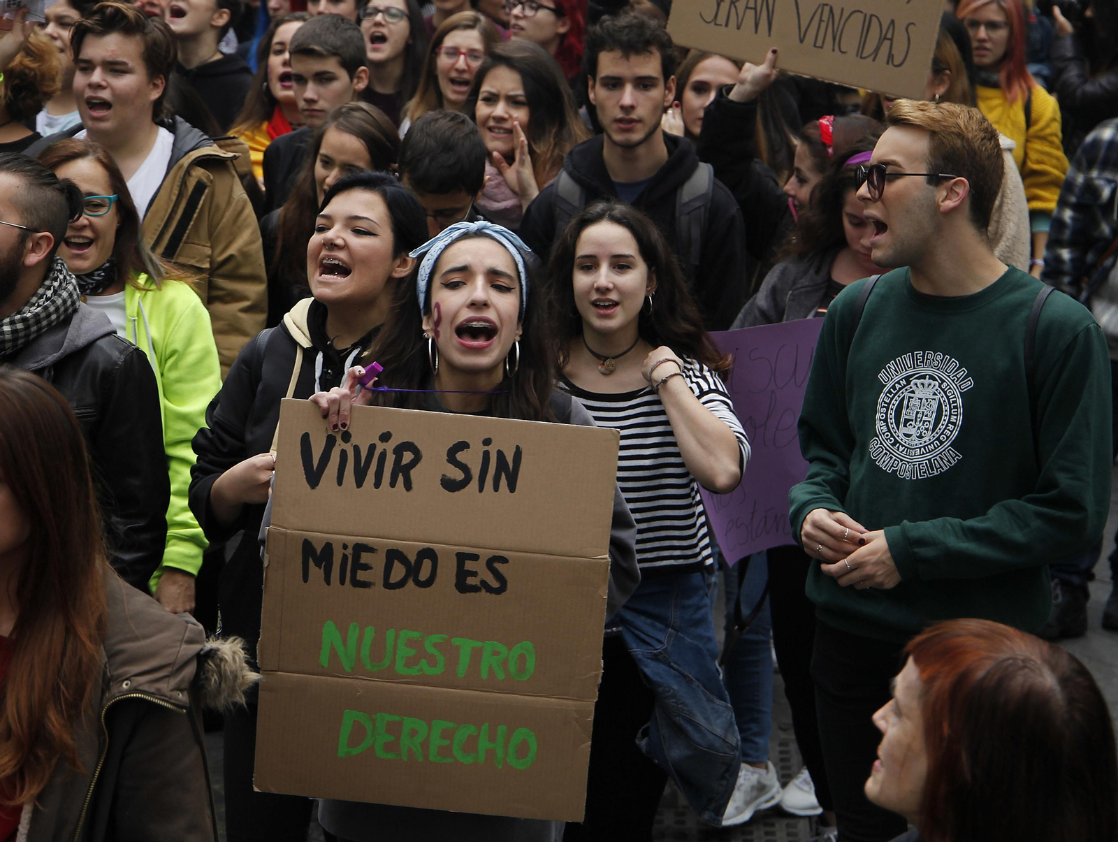 Una joven muestra una consigna escrita en un cartón.