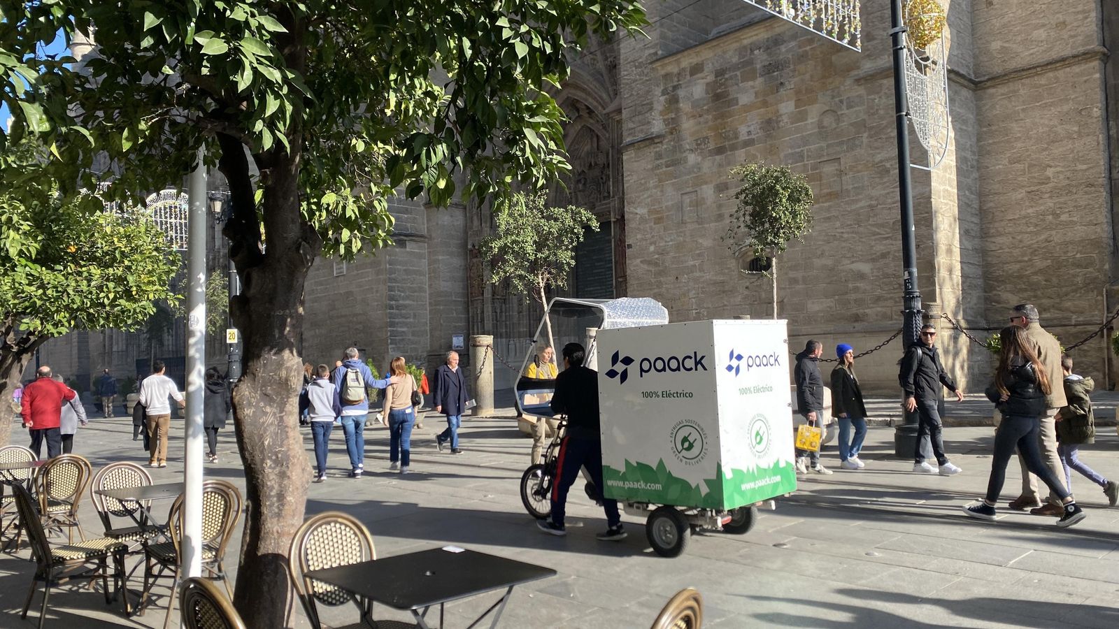 Un hombre avanza andando con un triciclo en la Avenida de la Constitución
