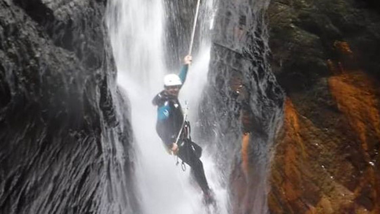 Un barranquista desciende en rápel por una cascada.