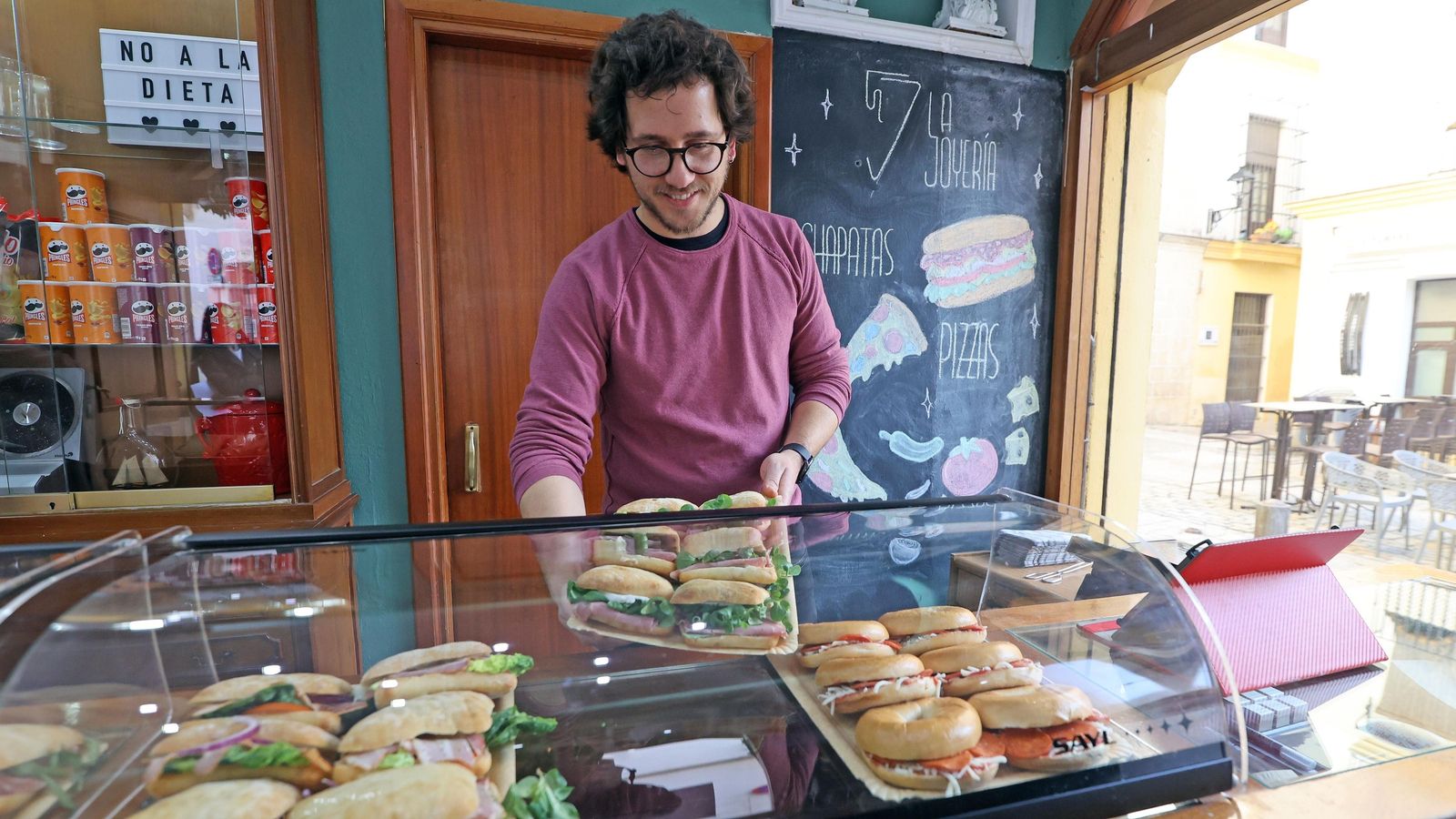 Adrián coloca una bandeja de chapatas en la antigua vitrina del local. Adrián coloca una bandeja de chapatas en la antigua vitrina del local.