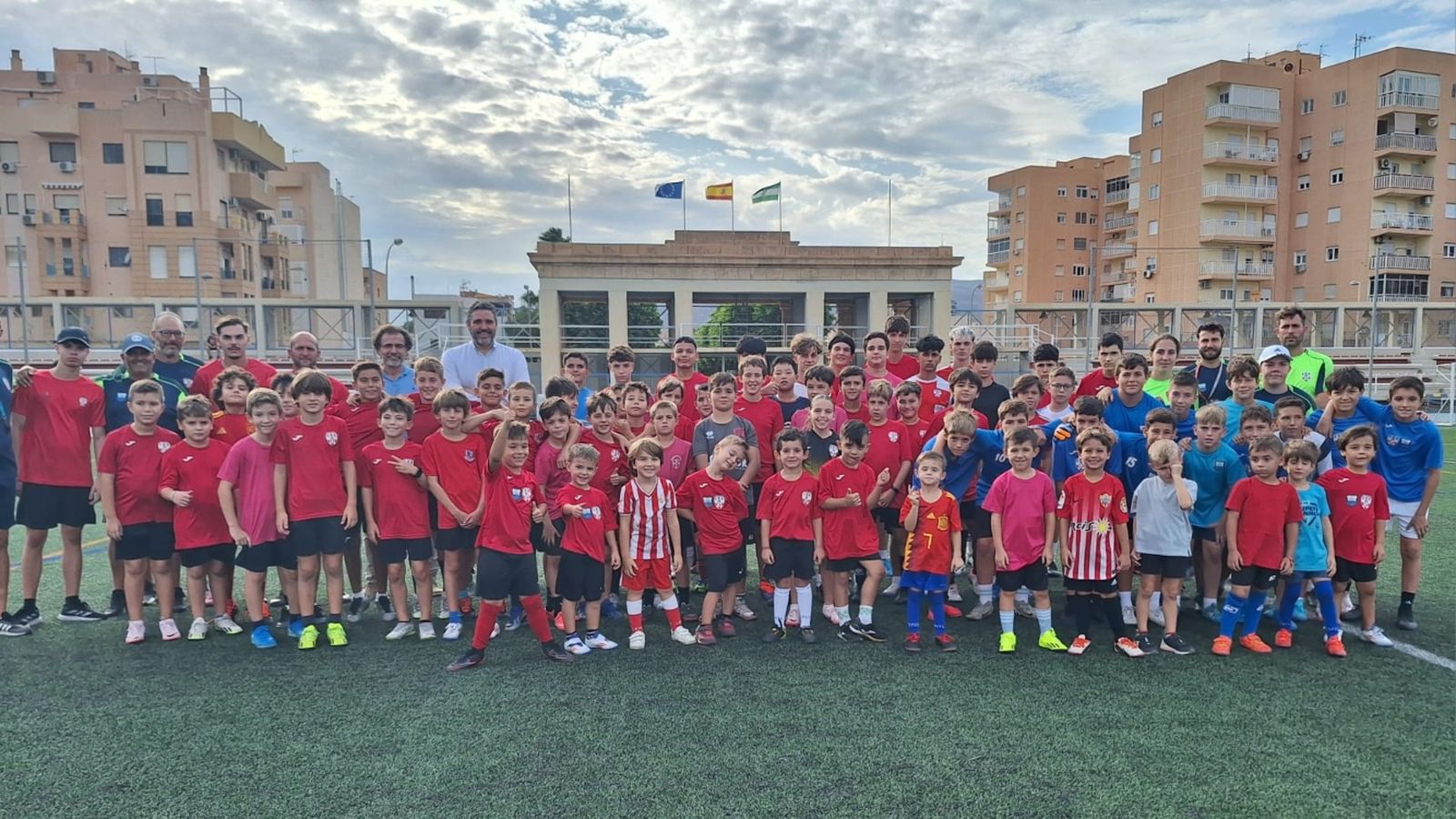 El delegado territorial rodeado de los más pequeños sobre el césped del estadio.