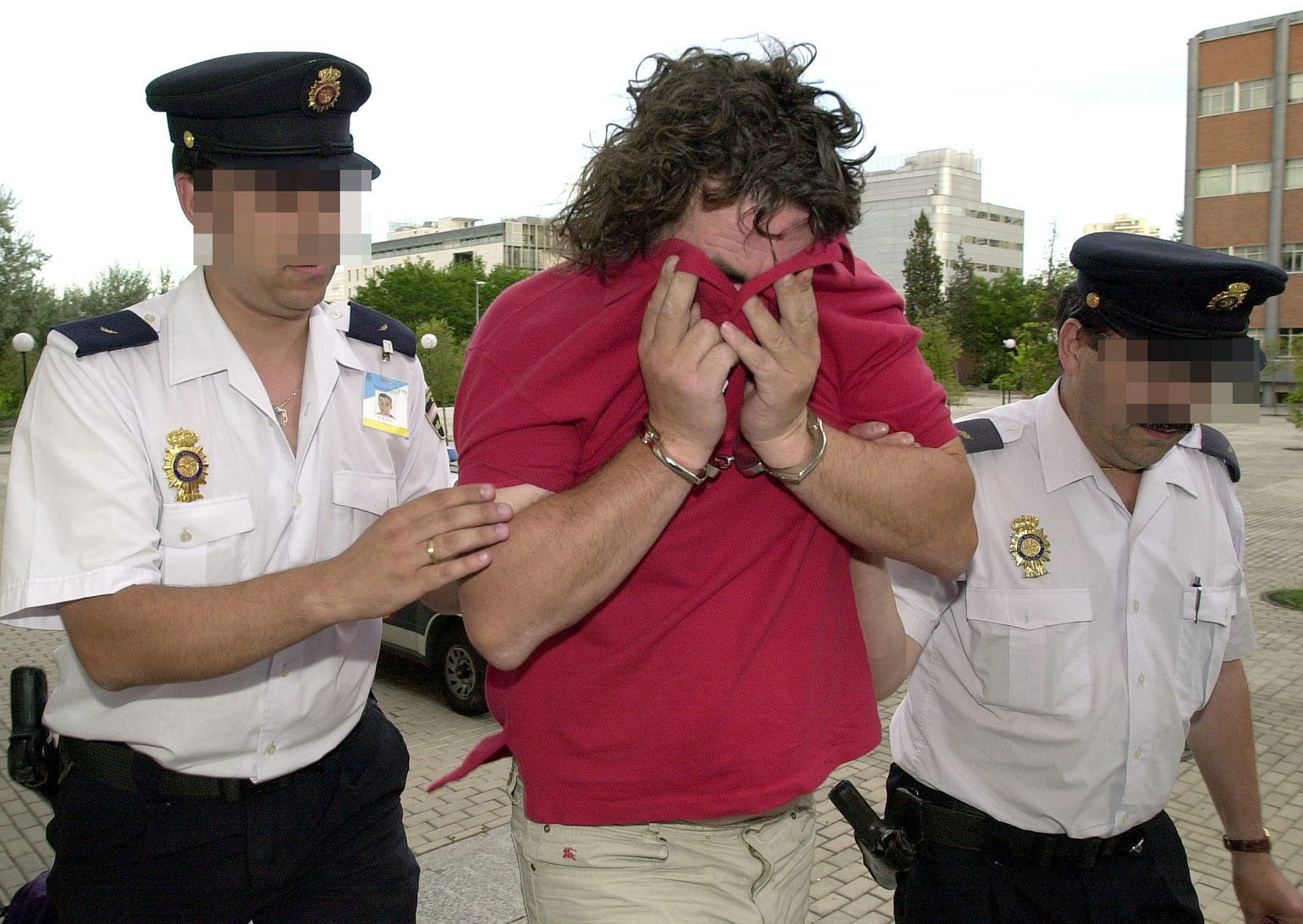 Miñanco oculta su rostro mientras es conducido por agentes de la Policía.