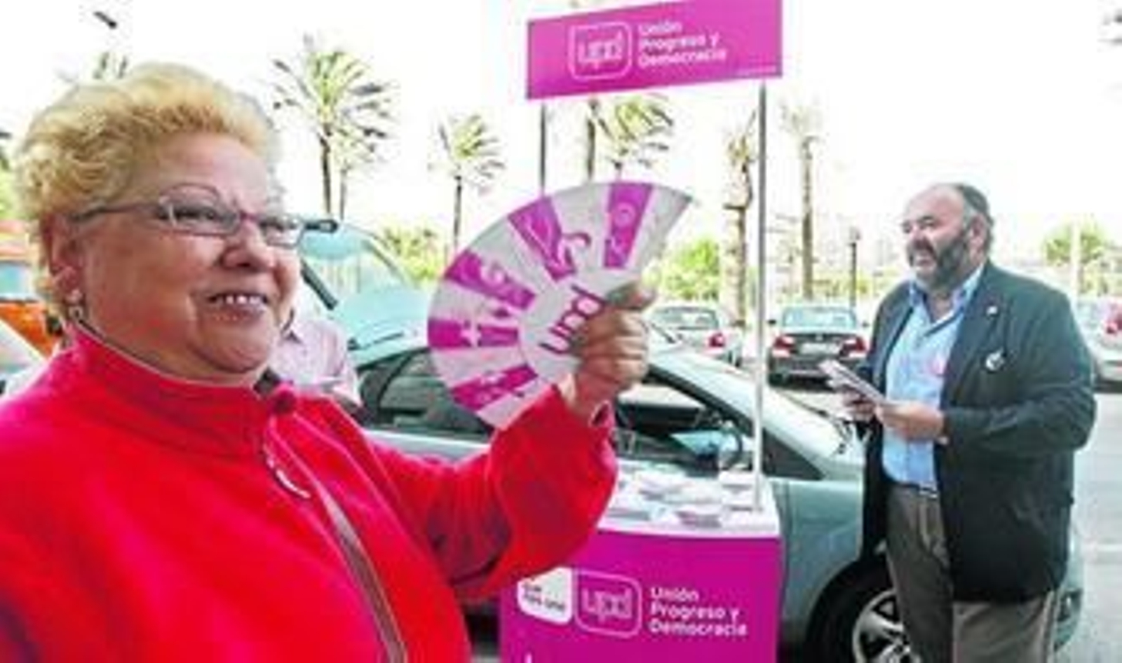 Una mujer usa un abanico de propaganda de UPyD con su candidato a la Alcaldía, Manuel Pérez Fabra, al fondo.