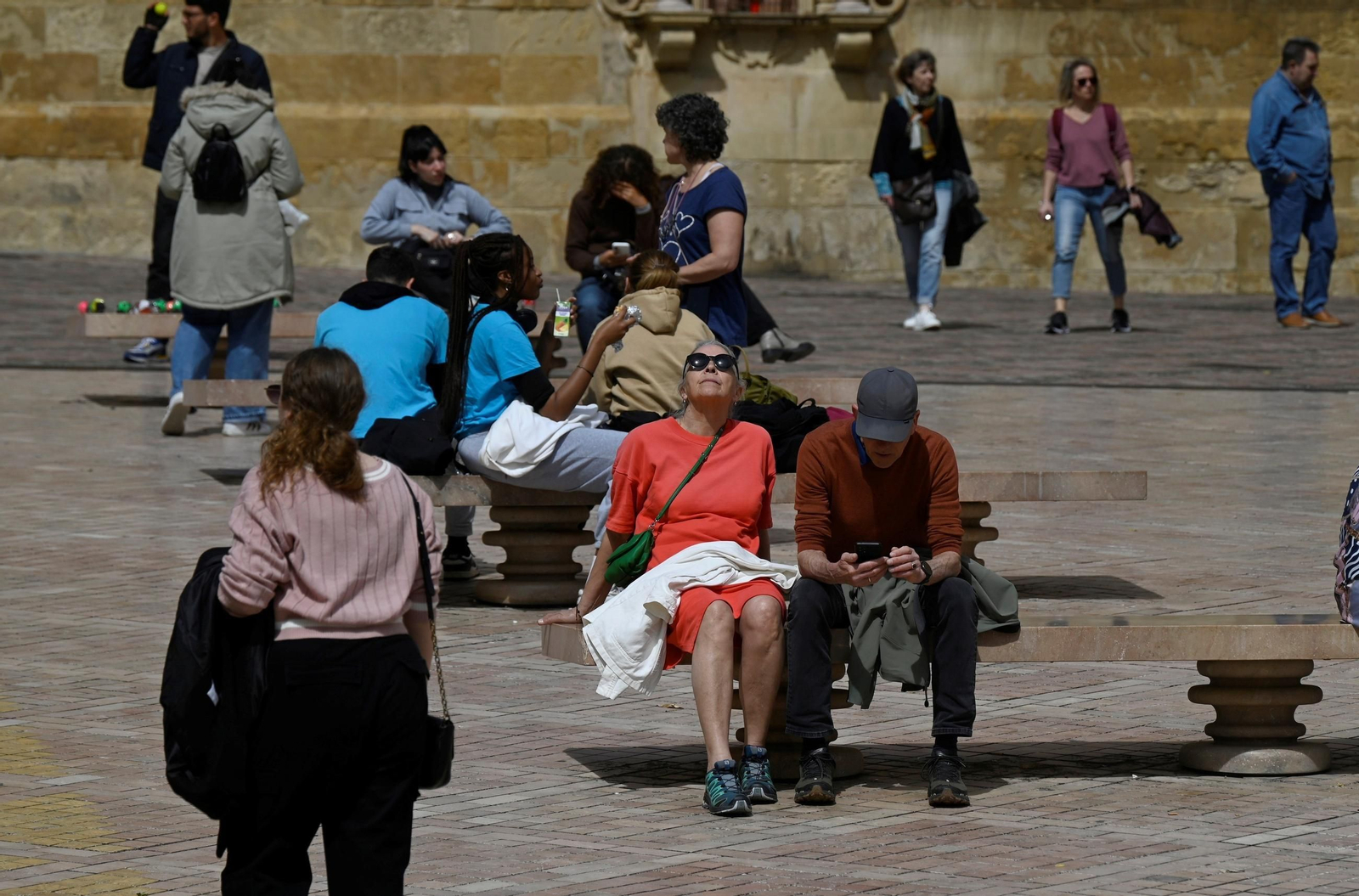 Turistas descansan en unos bancos junto a la Puerta del Puente de Córdoba.