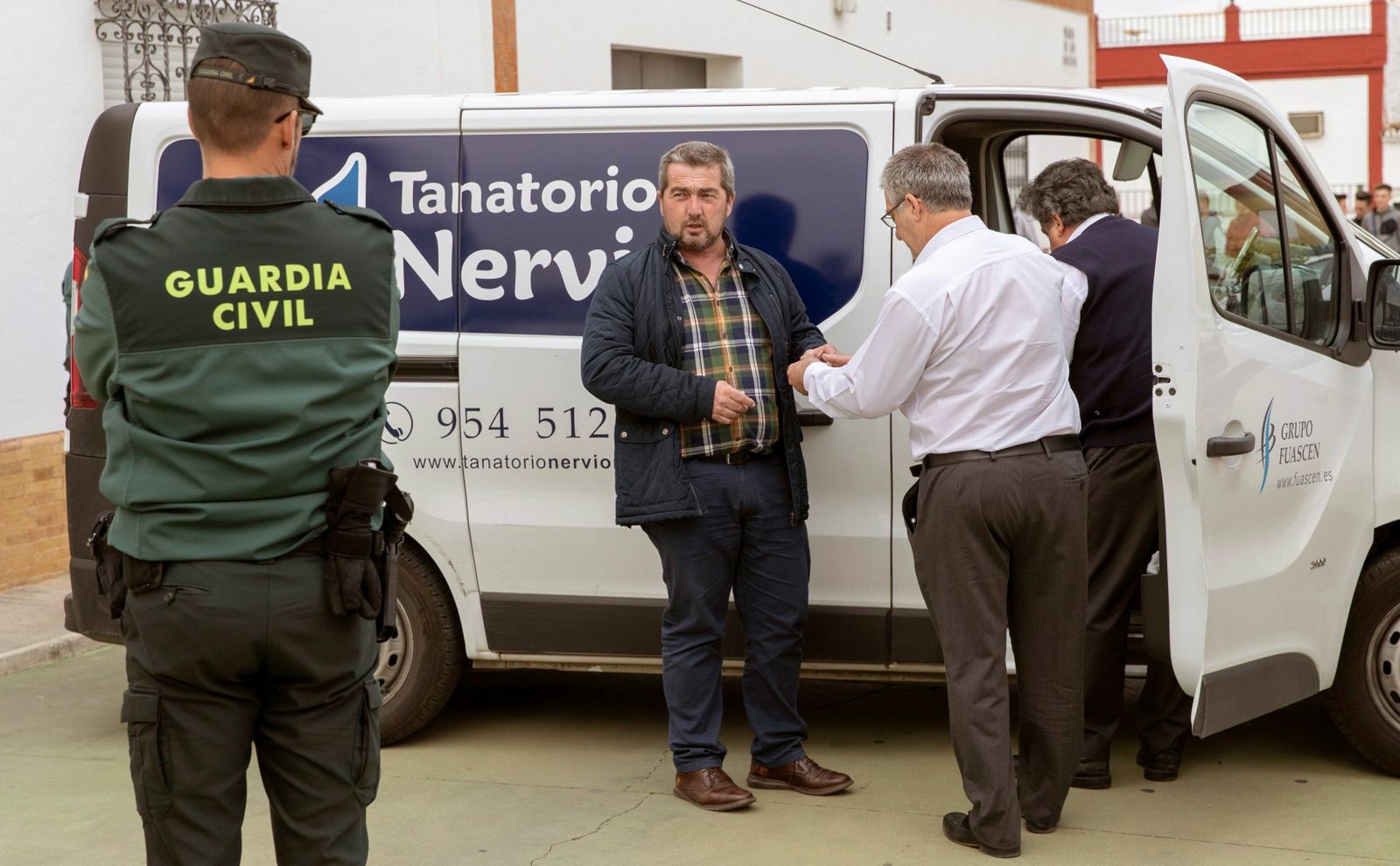 El alcalde, Juan José Fernández (con camisa de cuadros), ante el domicilio de la mujer hallada muerta en su domicilio.