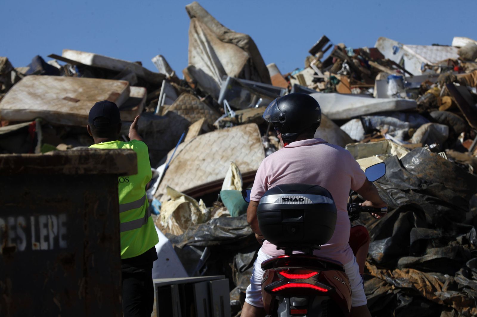 Dos vecinos de Lepe contemplan la enorme montaña de enseres destrozados por las inundaciones
