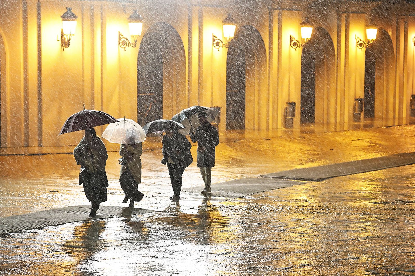Varias personas tratan de refugiarse de la intensa lluvia en Huelva .