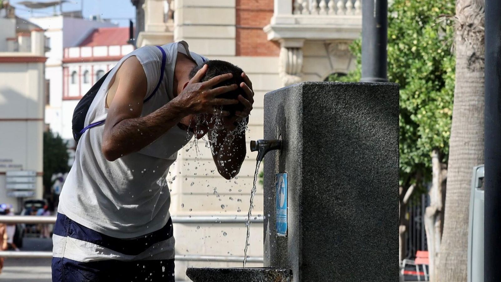 Un hombre de refresca en una fuente pública.