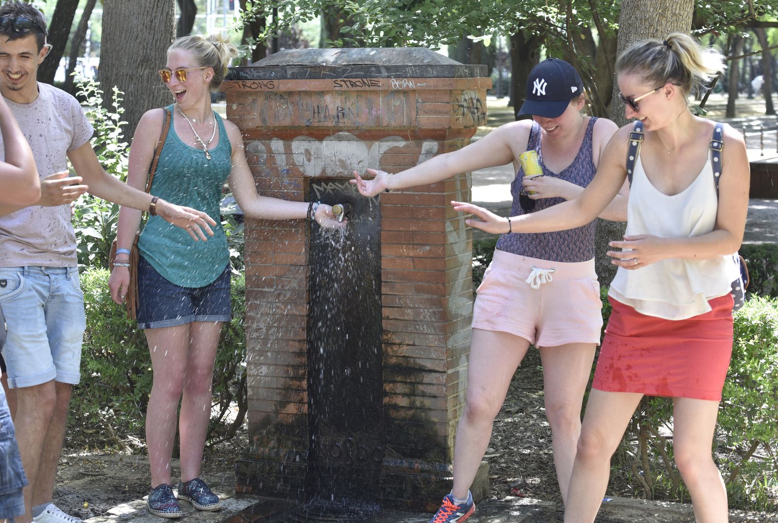 Un grupo de turistas se refresca en una fuente.
