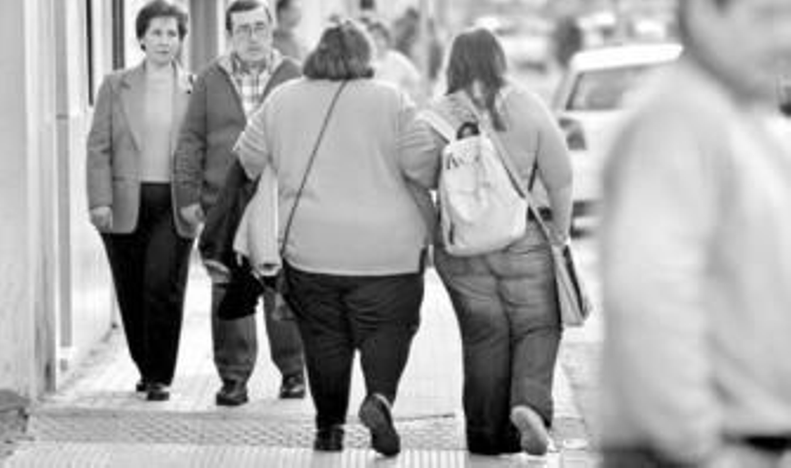 Dos personas obesas pasean por una calle de la ciudad.