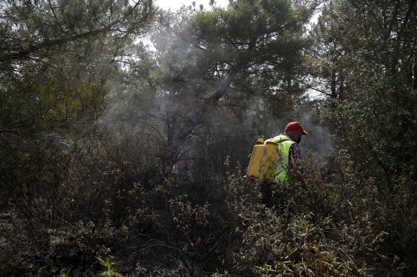 Un voluntario ayuda a refrescar el suelo en un incendio de León.