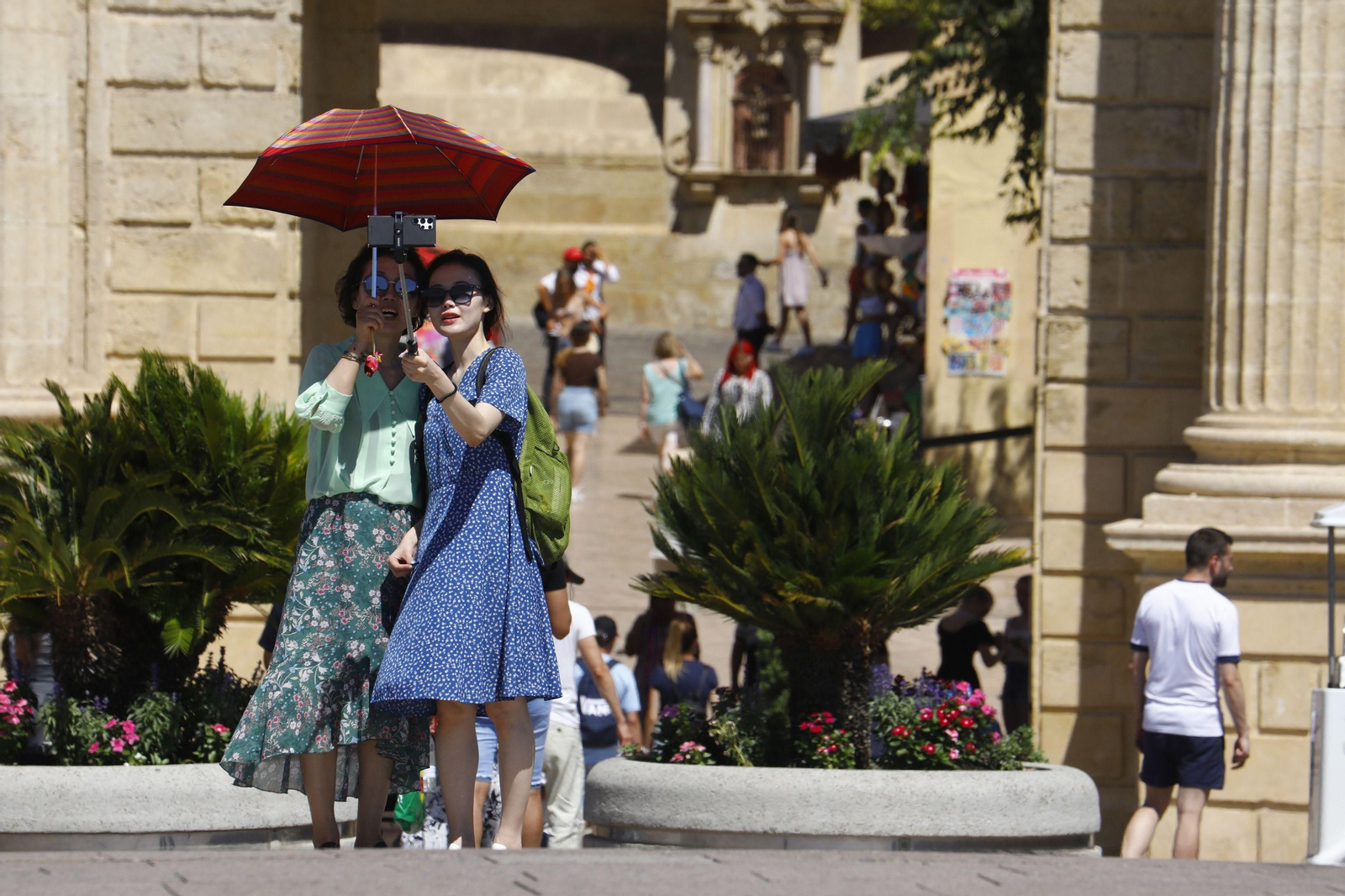 Unas turistas se protegen del sol mientras pasean por el centro de Córdoba.