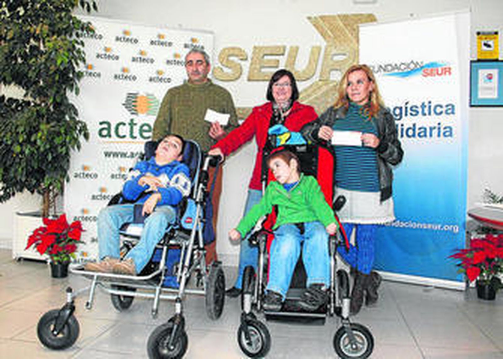 Los jóvenes Daniel y Antonio Jesús acompañados por sus familias después de recibir los dos cheques.