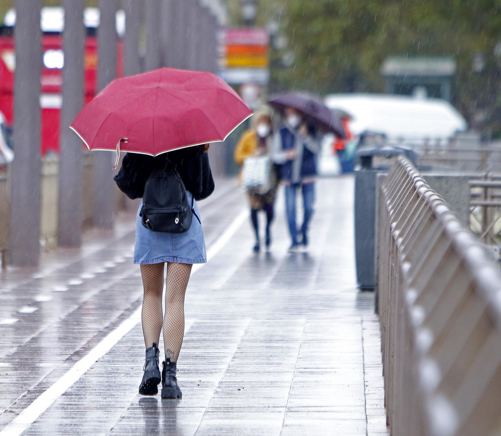 Una joven camina por Sevilla con paraguas.