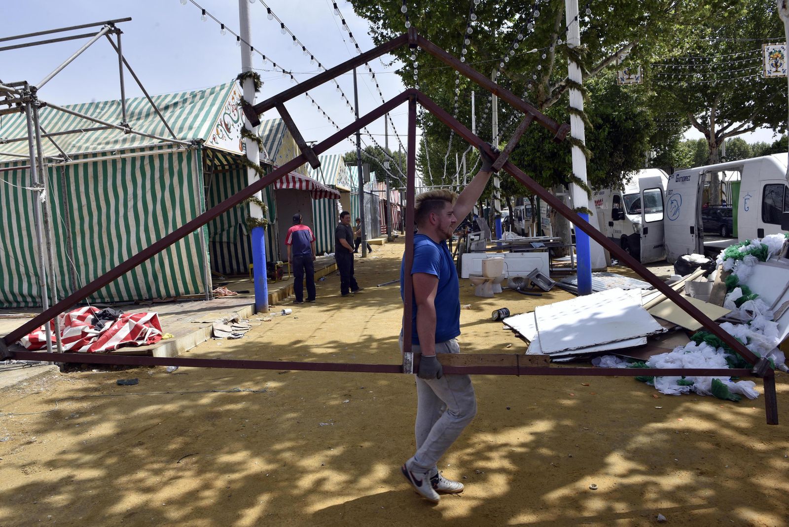 Un trabajador lleva a pulso la estructura de la pañoleta de una caseta de la Feria.
