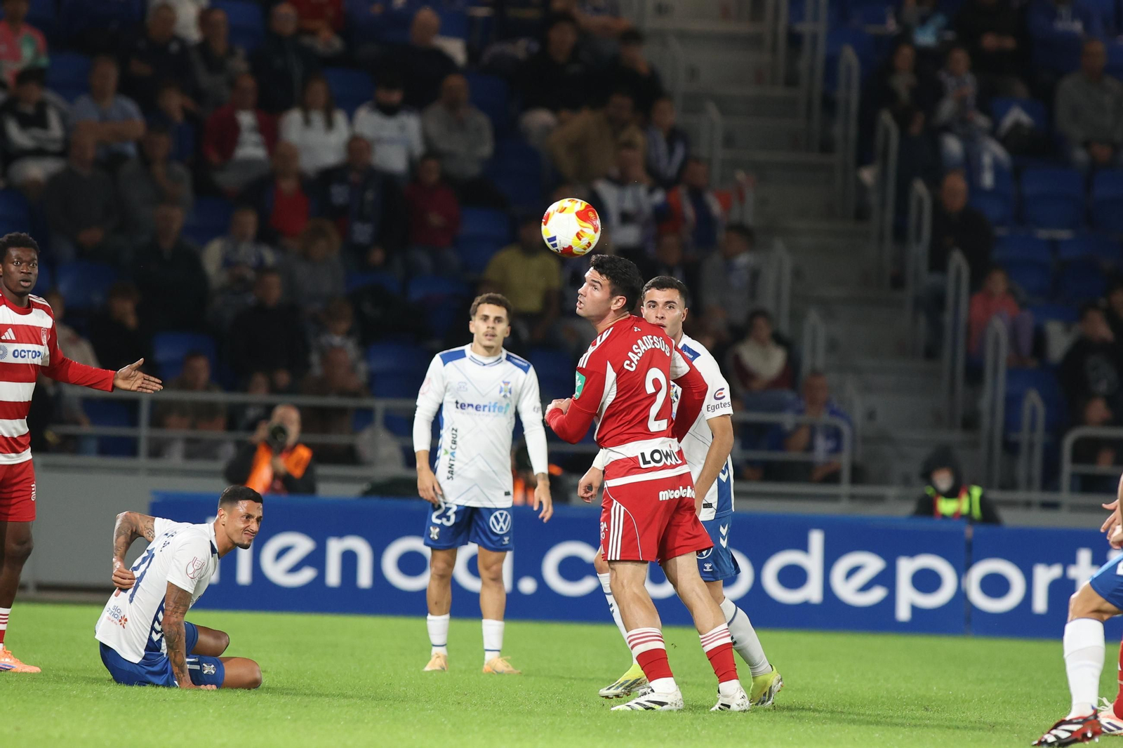 Casadesús cabeceando el balón ante la mirada de dos jugadores locales.
