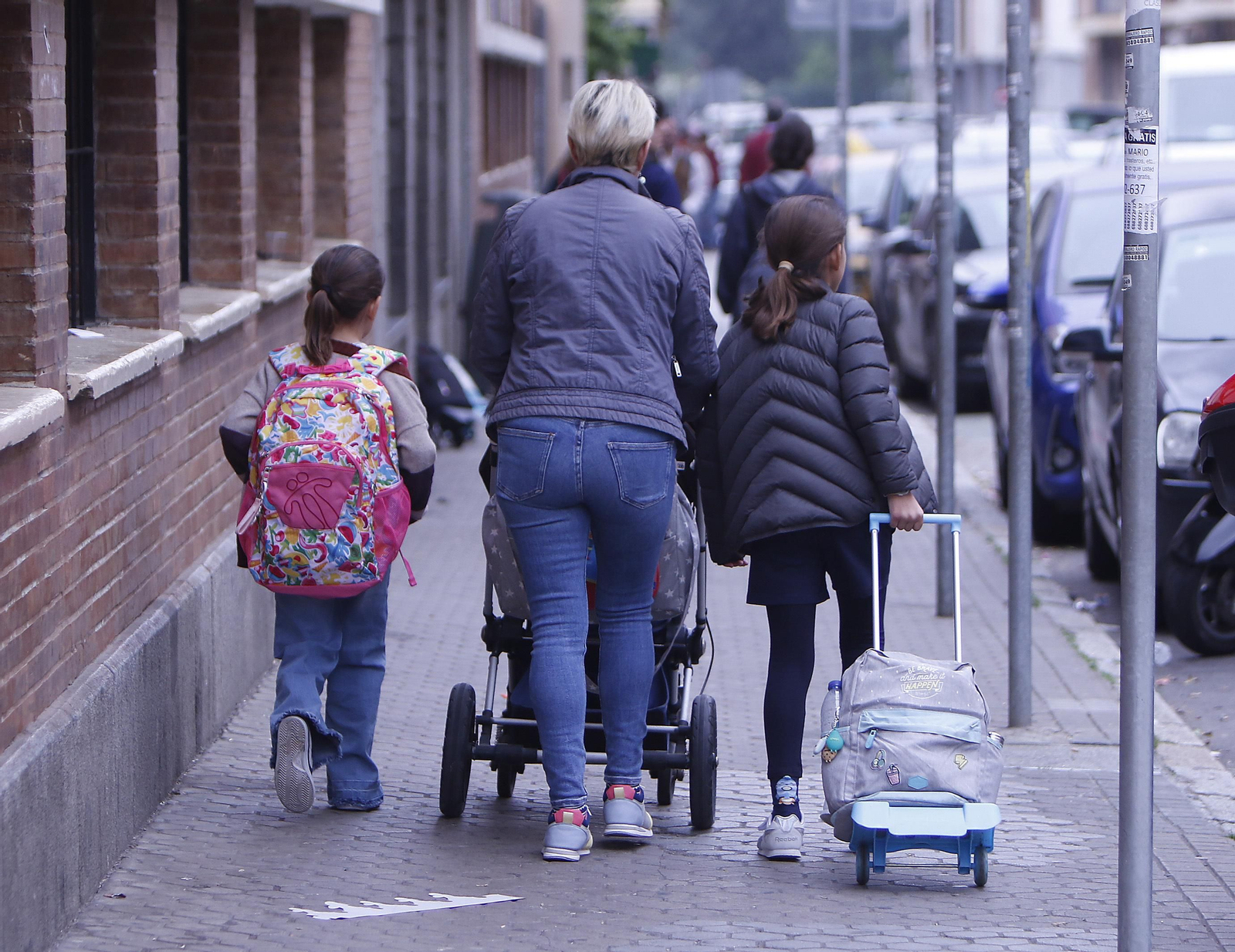 Una mujer camino del colegio con dos menores en edad escolar.