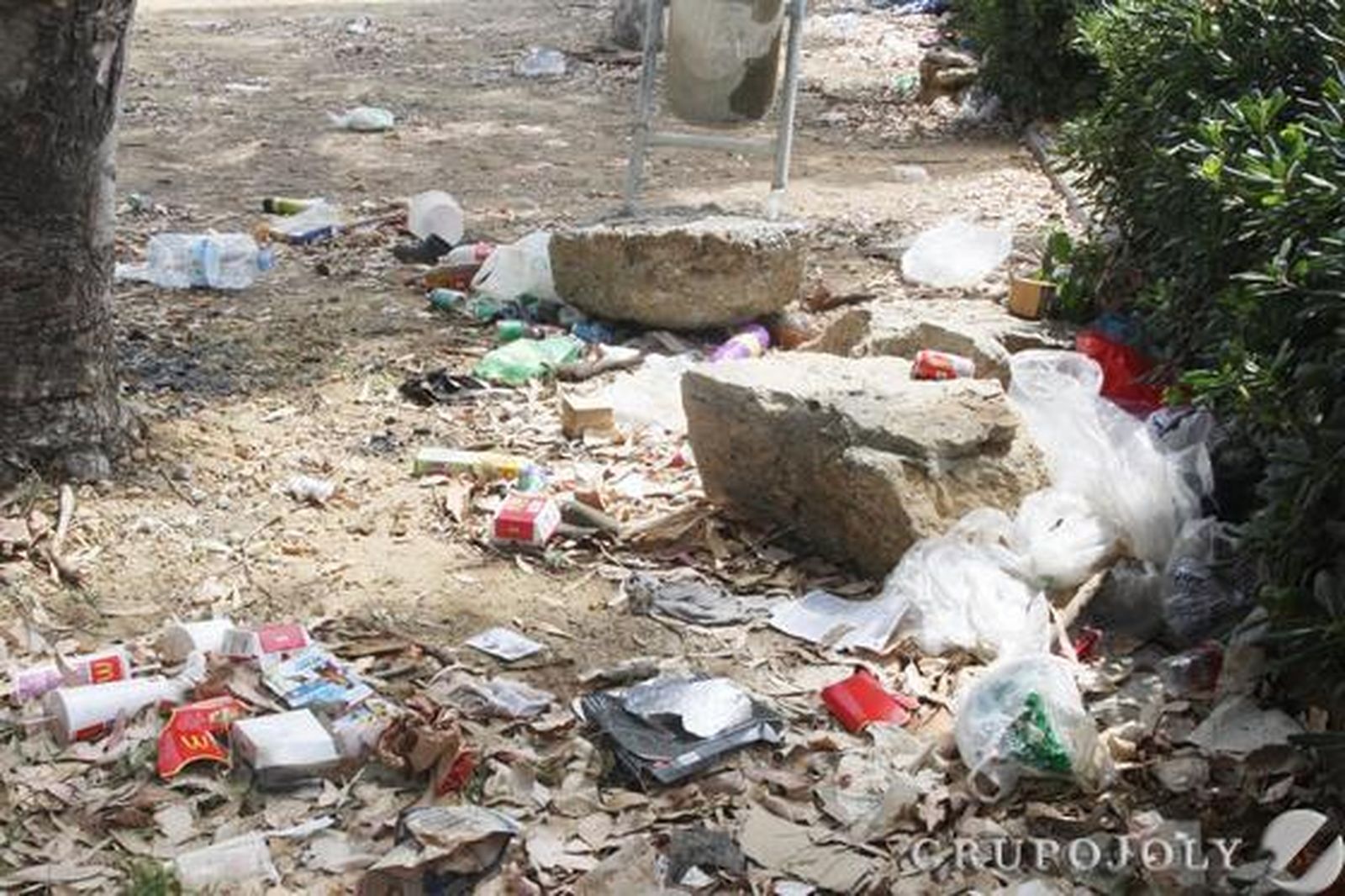 Pláticos y restos de suciedad esparcidos por el suelo del recinto frente a una papelera.

Foto: Paco Guerrero