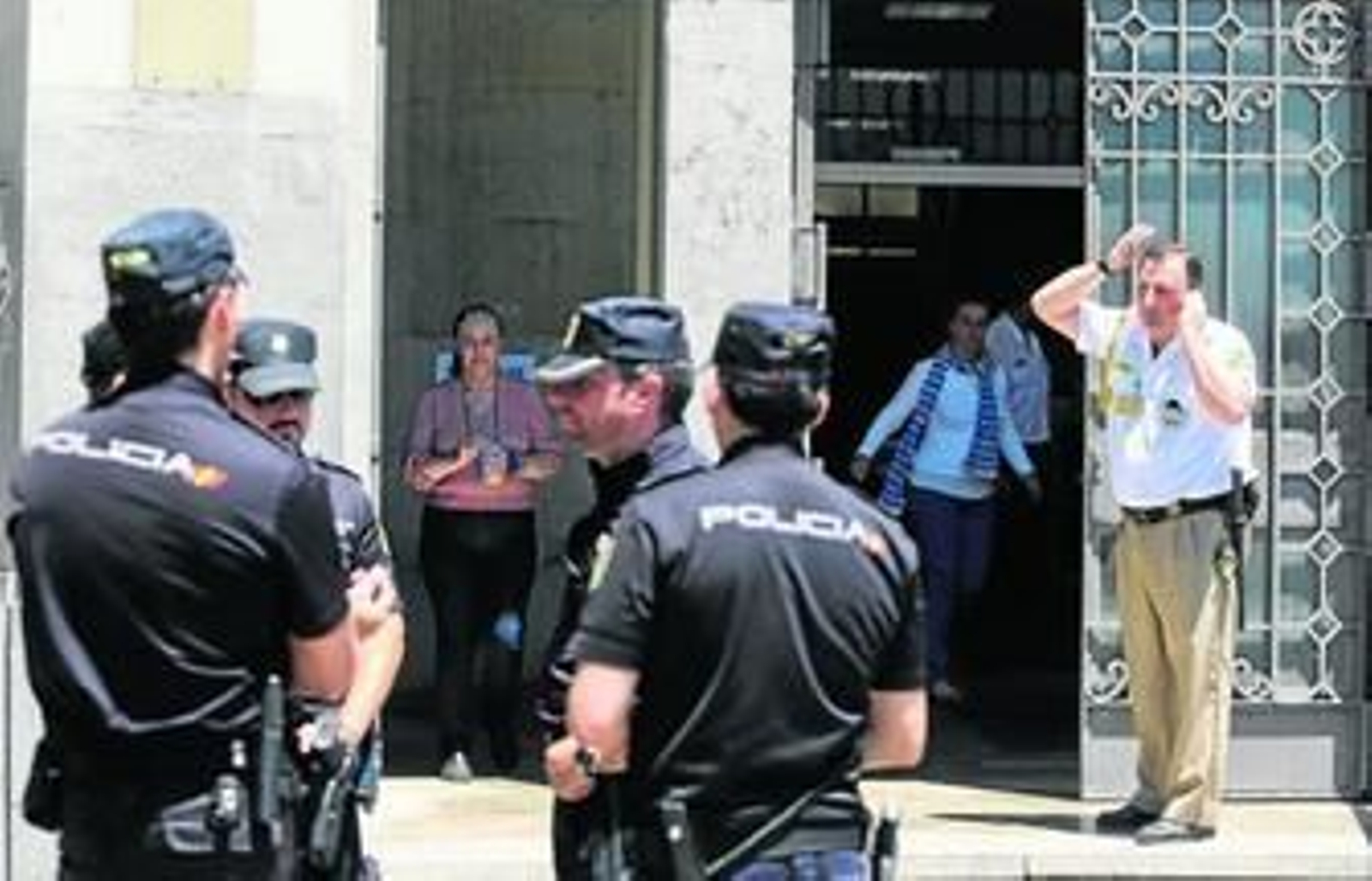 Policías nacionales, ayer, ante la sede de Bienestar Social. A la derecha, uno de los vigilantes de seguridad que apagó al hombre envuelto en llamas.