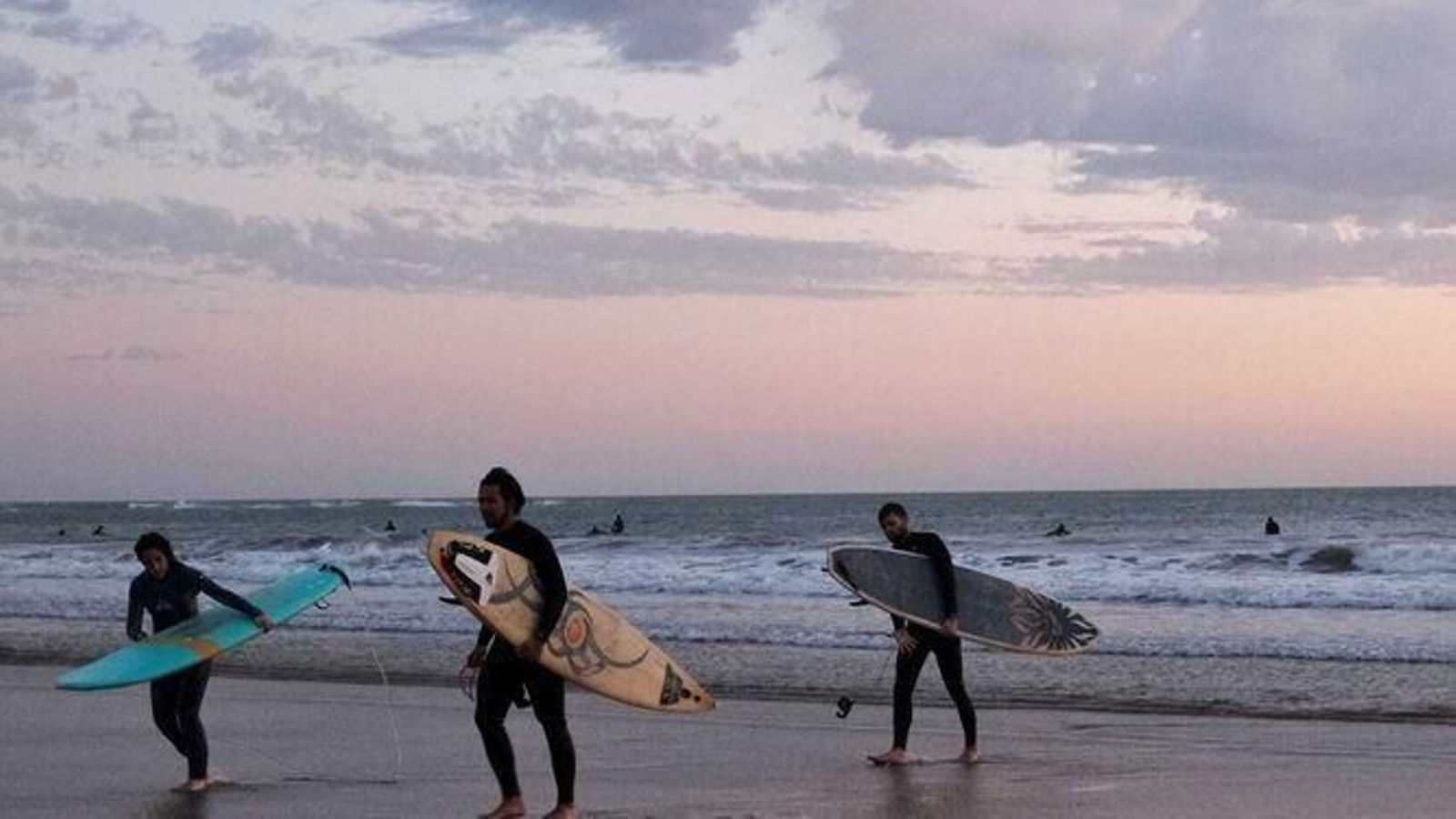 Varios surferos en la playa.