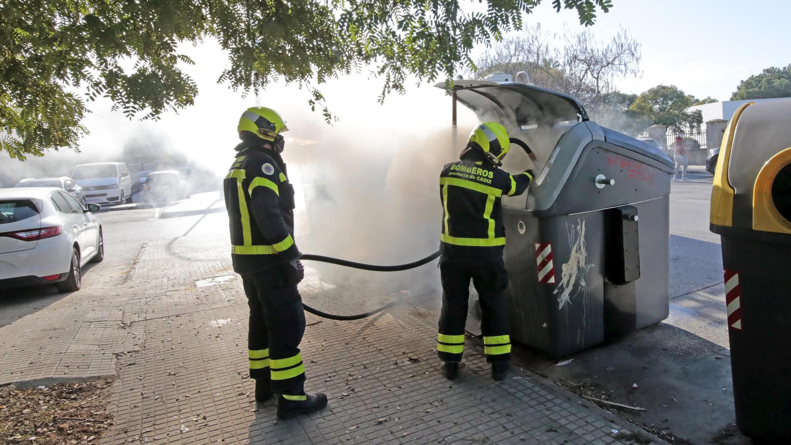Bomberos sofocando el fuego en un contenedor de la calle Jaén, esta tarde.