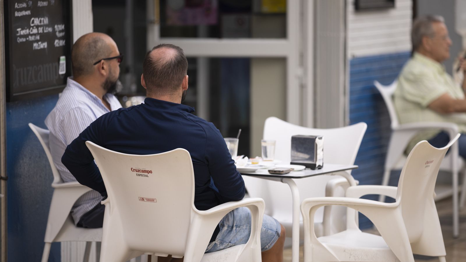 Dos hombres conversan en una terraza en la capital onubense.