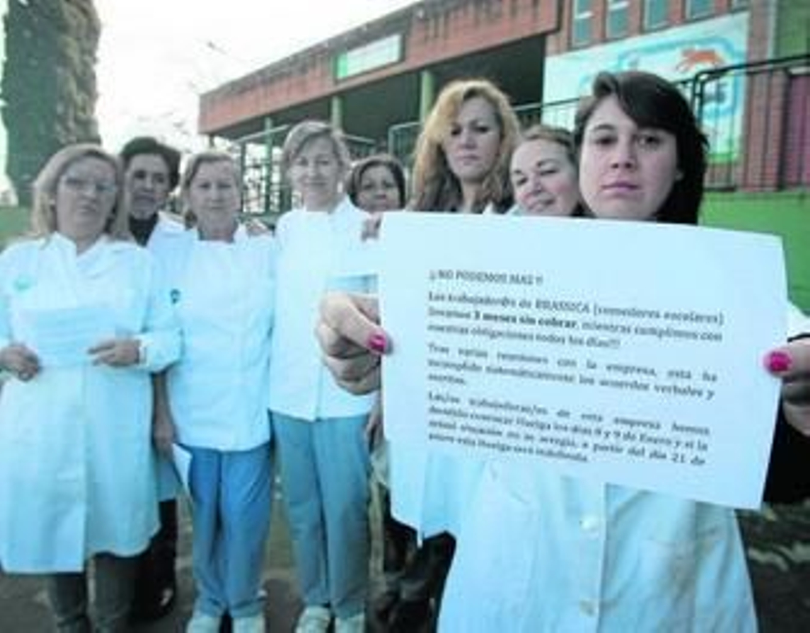 Monitoras de comedor y ayudantes de cocina del CEIP La Raza muestran un folleto reivindicativo.