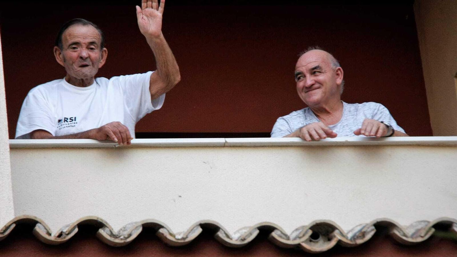 Residentes asomados a un balcón del centro Puerto Luz, responden al cariñoso aplauso de los vecinos.